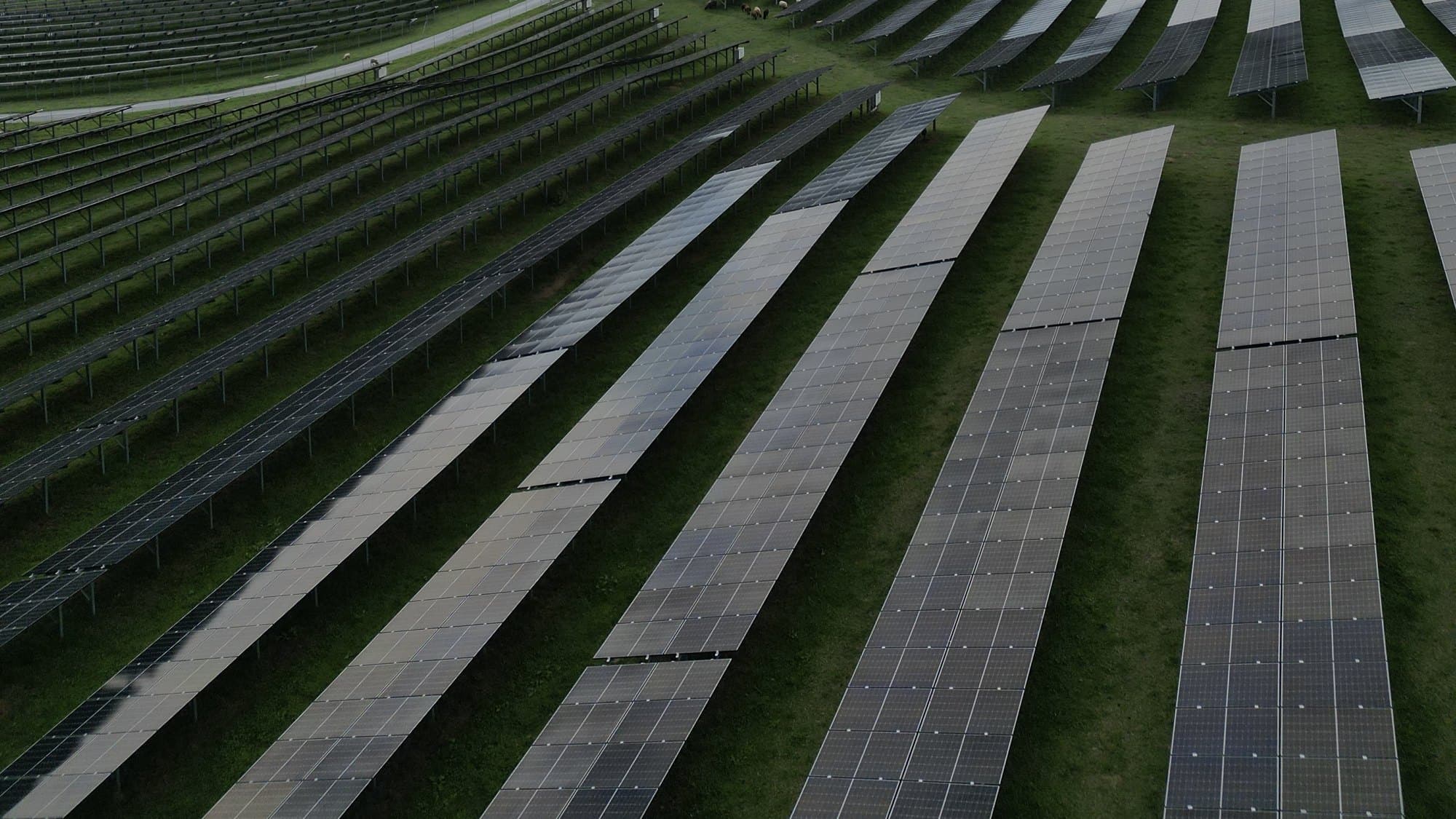 Modulreihen einer Photovoltaik-Freiflächenanlage auf einer Wiese in der Steiermark aus der Vogelperspektive Modulreihen einer Photovoltaik-Freiflächenanlage auf einer Wiese in der Steiermark aus der Vogelperspektive
