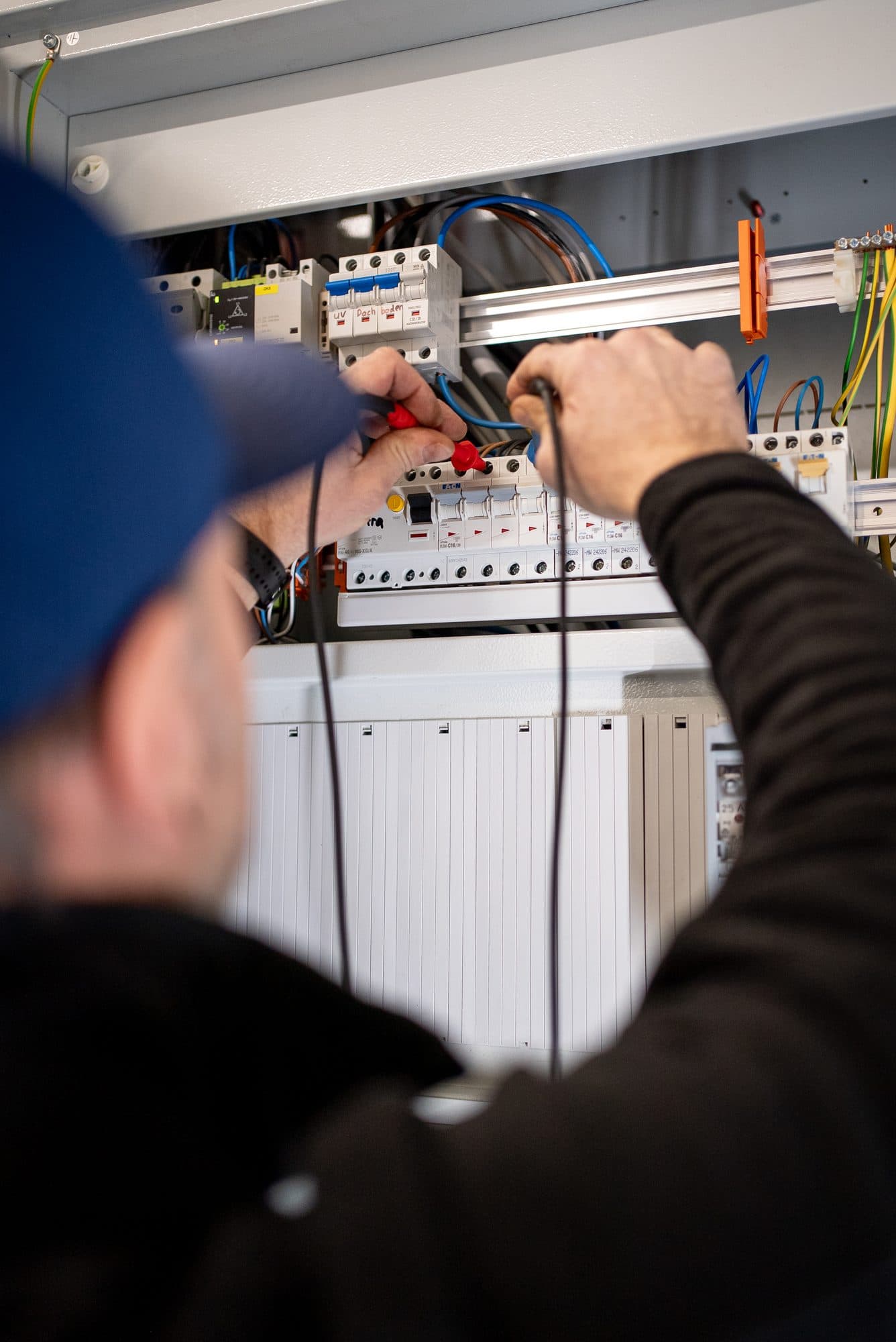 Techniker misst mit einem Prüfgerät an einem Sicherungskasten Techniker misst mit einem Prüfgerät an einem Sicherungskasten