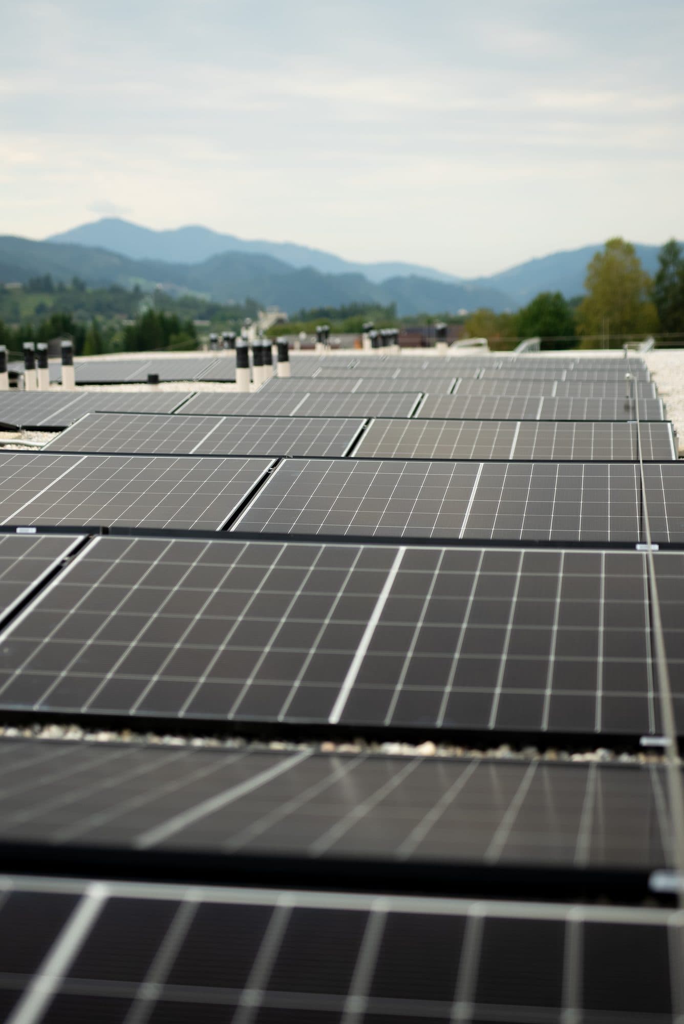 Photovoltaikanlage auf einem Dach mit Bergpanorama im Hintergrund Photovoltaikanlage auf einem Dach mit Bergpanorama im Hintergrund