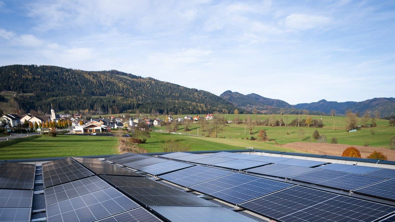 Photovoltaikanlage auf einem Dach in der Steiermark mit Blick auf ein Dorf im Tal Photovoltaikanlage auf einem Dach in der Steiermark mit Blick auf ein Dorf im Tal
